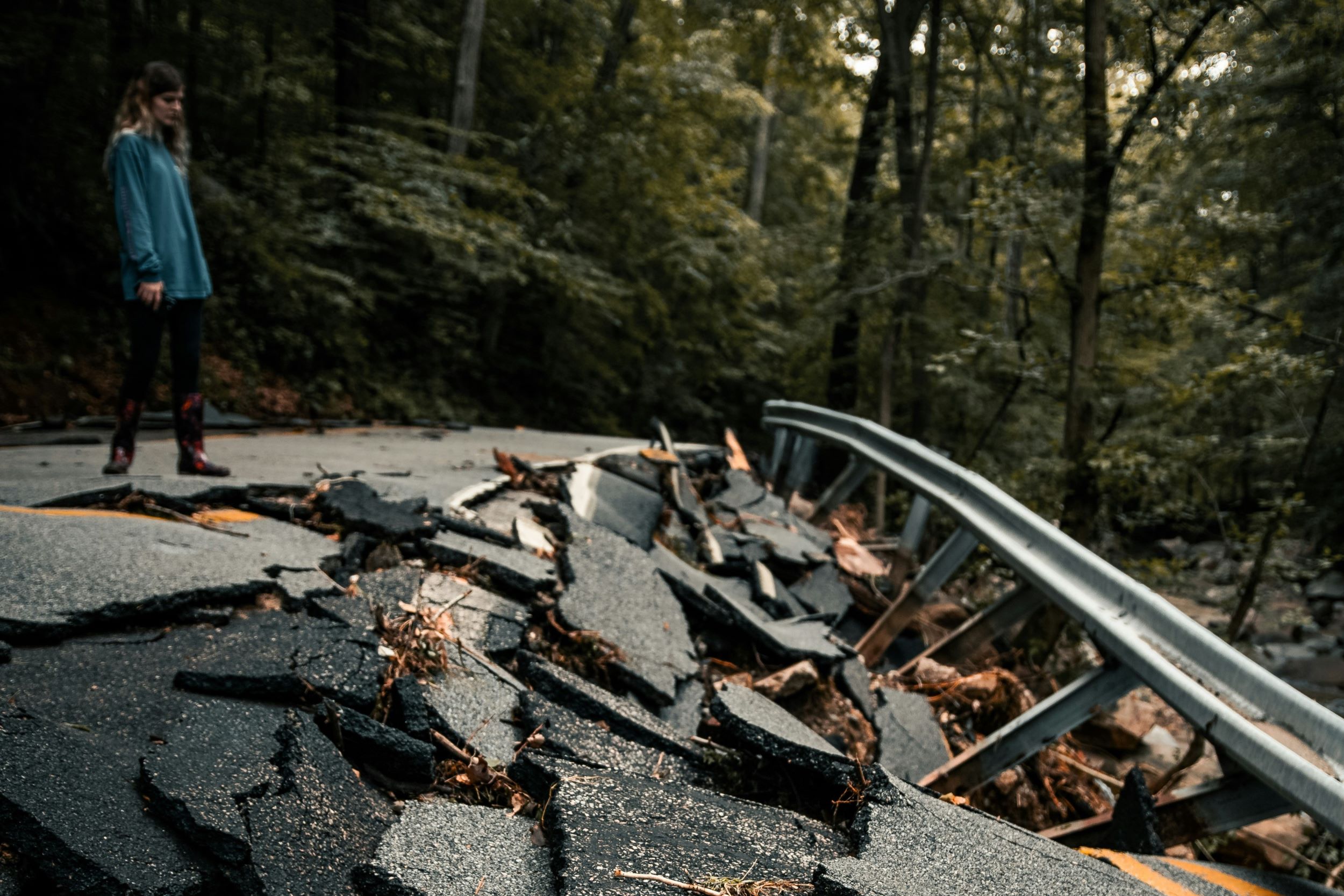 A person inspects an earthquake-damaged road