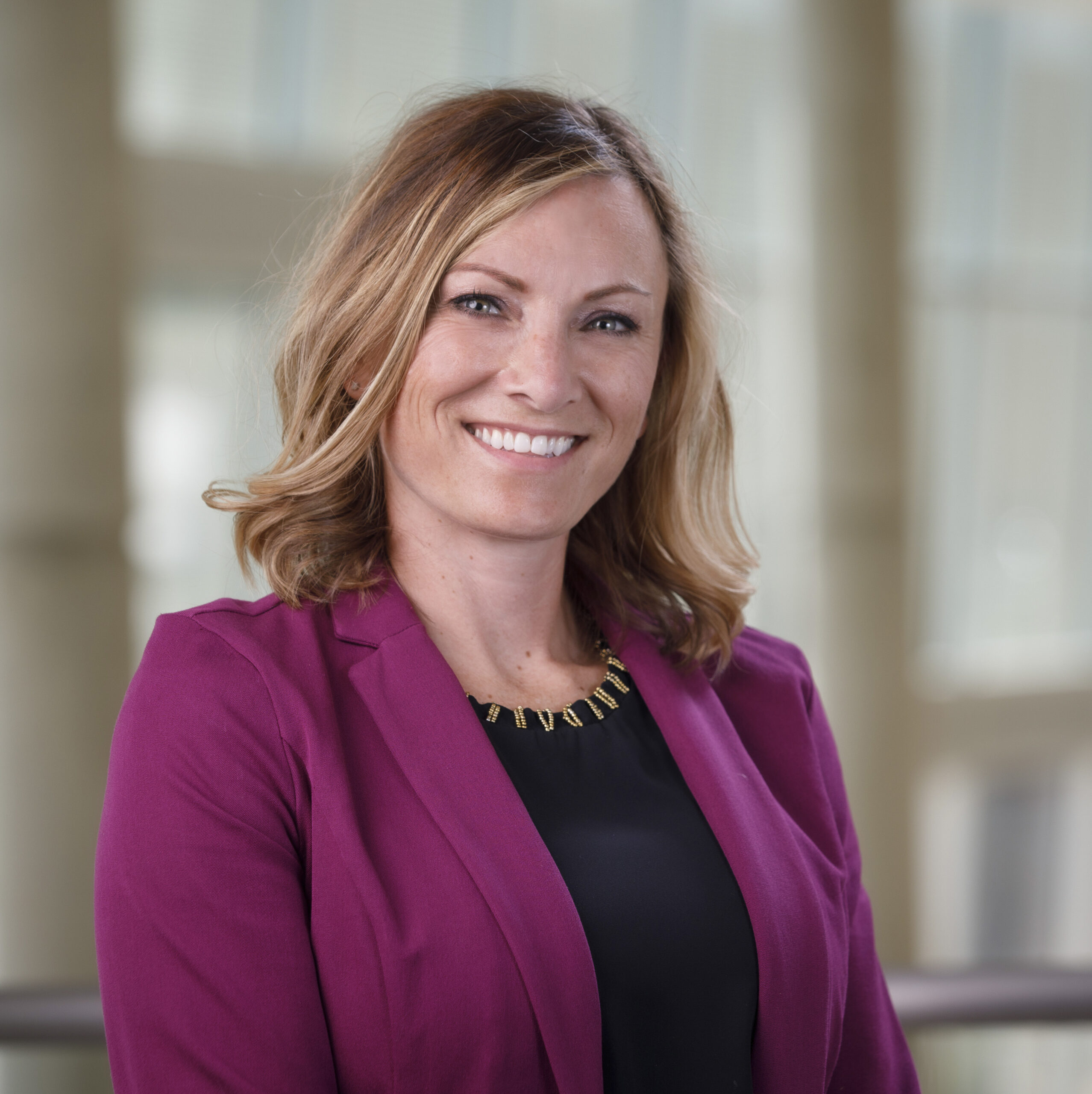Image of Angela Vasa, who is wearing a black shirt with a cranberry blazer